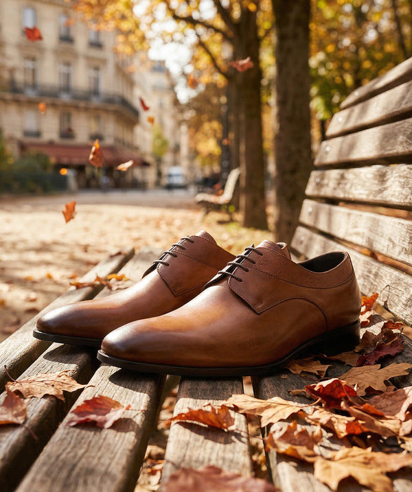 Finsbury – Derby Umberto - Marron Patiné, chaussures marron en cuir posées sur un banc en bois avec des feuilles d'automne