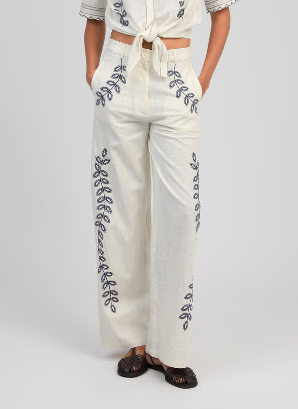 An'ge – Rossalie Trousers Ecru, off-white wide-leg trousers embroidered with blue botanical motifs, worn from the front